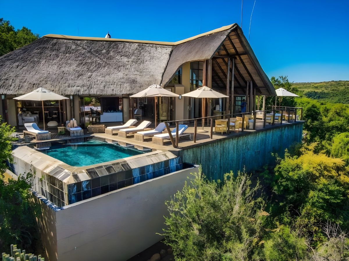The main lodge, its pool and deck above the bush