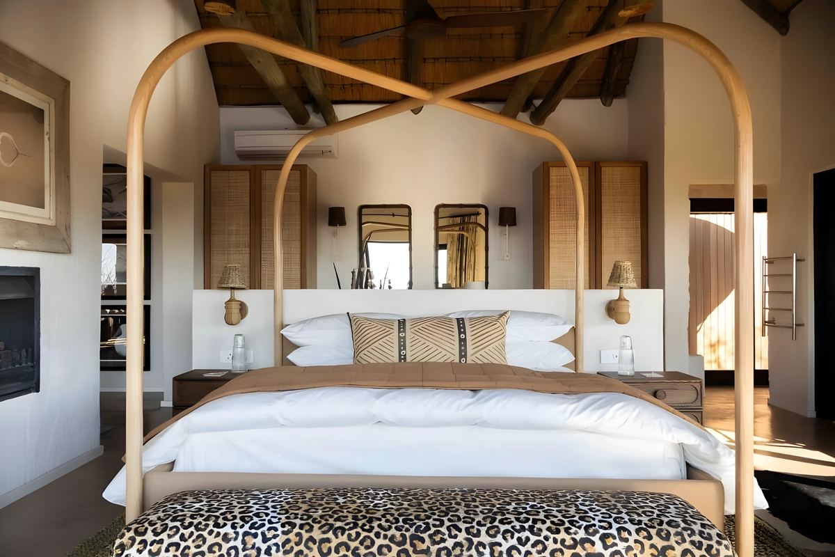 A canopy bed in a suite, with the fireplace beside it