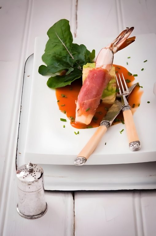 Prawn wrapped in ham, with a red pepper sauce