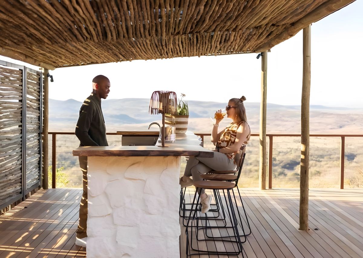A guest at the pool bar with the barman, the hills behind