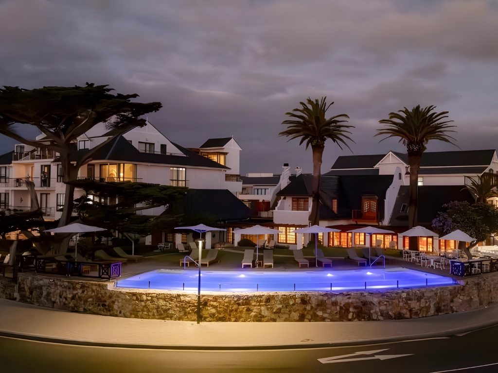 The pool lit up at dusk in front of the hotel