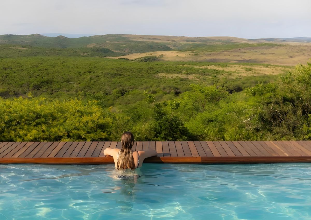 A guest in the pool looking out over the green hills