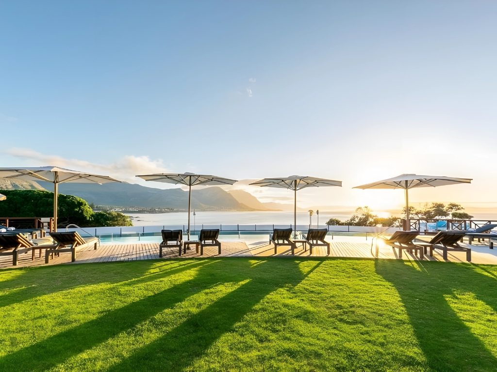 The lawn and pool deck at Harbour House at sunrise, looking over Walker Bay to the mountains