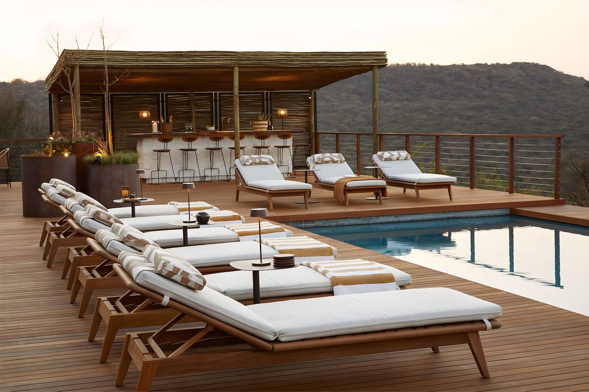 Loungers beside the pool, with the bar under its thatch behind