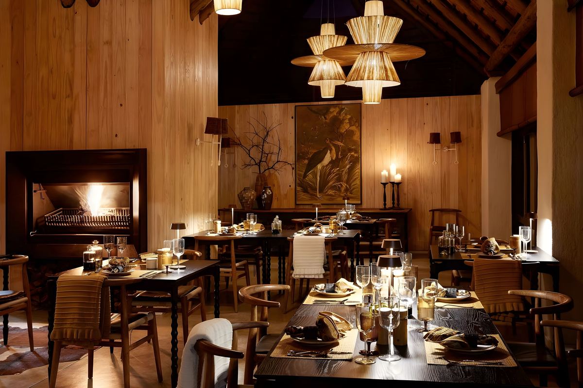 The dining room at night, candlelit, with a fire in the hearth