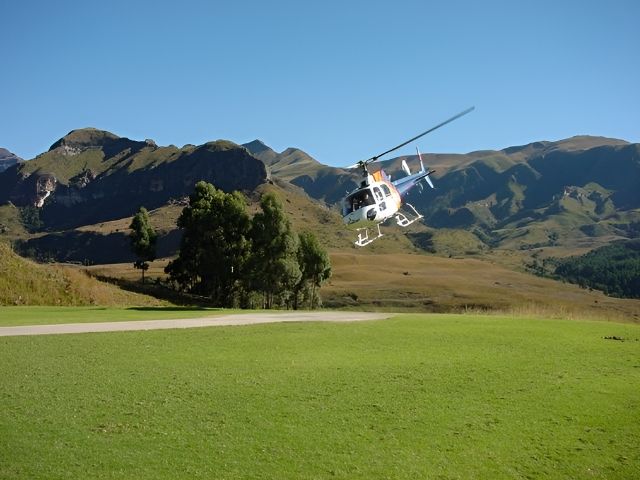 A helicopter landing on the lawn below the Drakensberg