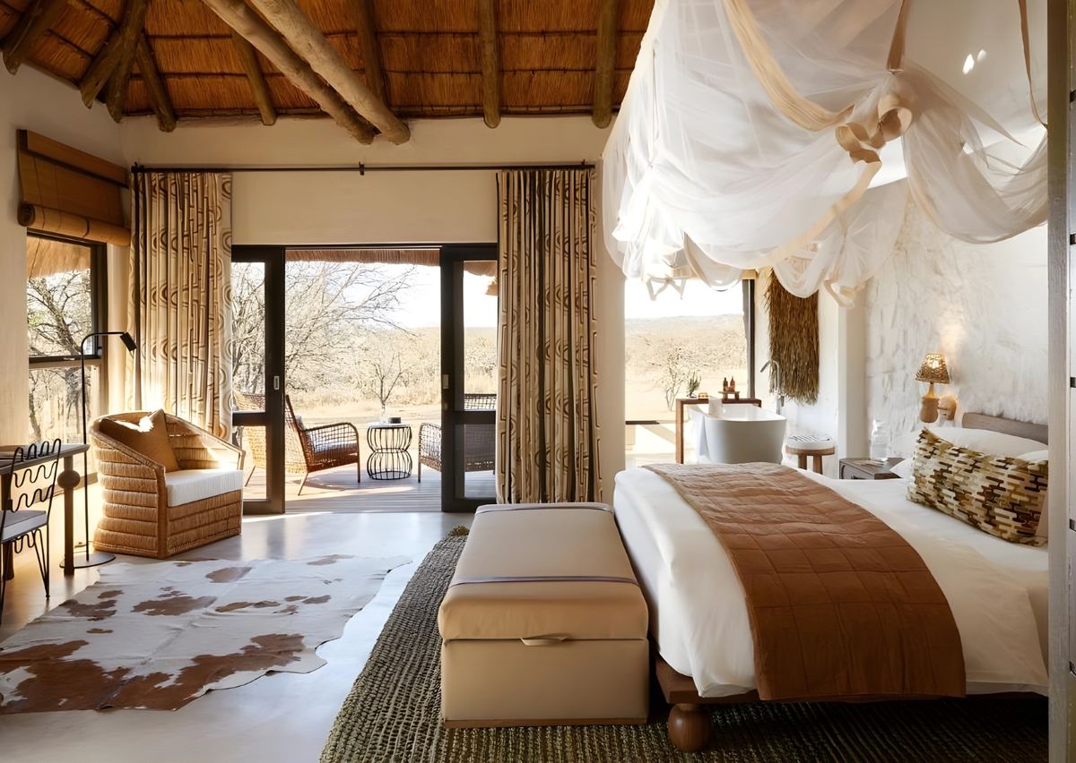 A suite with a netted canopy bed, a freestanding bath and doors open to the deck