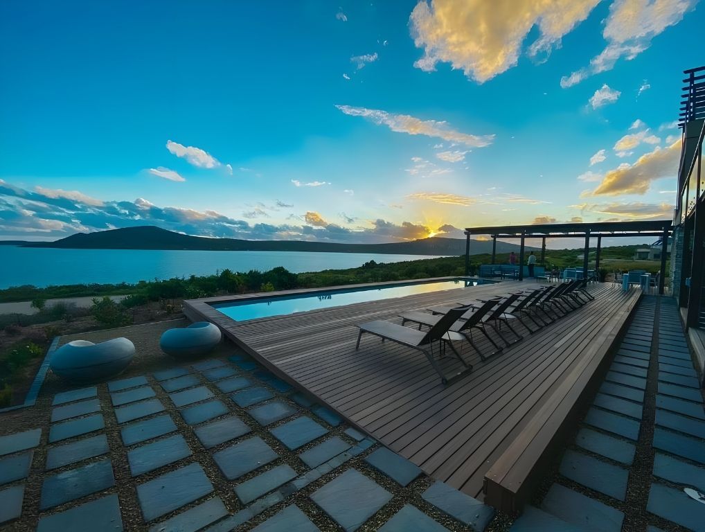 The pool deck at The Shark Bay at sunset, with the lagoon and hills beyond
